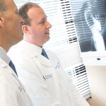 dr. jason lowenstein & dr. george naseef examining spine x-ray
