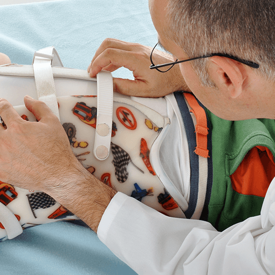 Doctor fitting a scoliosis brace for a child during a clinical appointment.