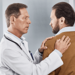 doctor examining patient with upper back pain