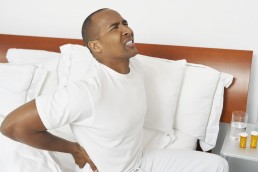 man suffering from lower back pain in bed