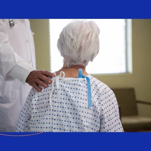 Elderly patient in a hospital gown meeting with a spine surgeon at The Advanced Spine Center in New Jersey.